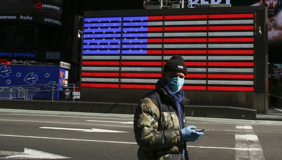Un hombre usa una máscara facial mientras camina por un Times Square desierto por la pandemia de coronavirus en Nueva York, Estados Unidos. (Foto: AFP)