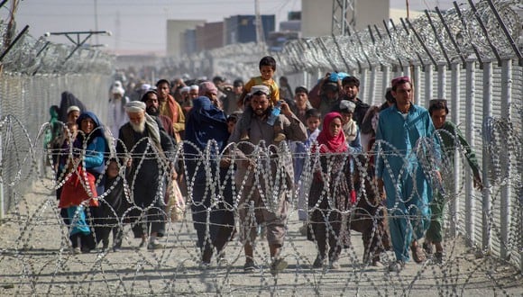 Los afganos caminan a lo largo de las vallas cuando llegan a Pakistán a través del paso fronterizo de Chaman el 24 de agosto de 2021. (AFP).