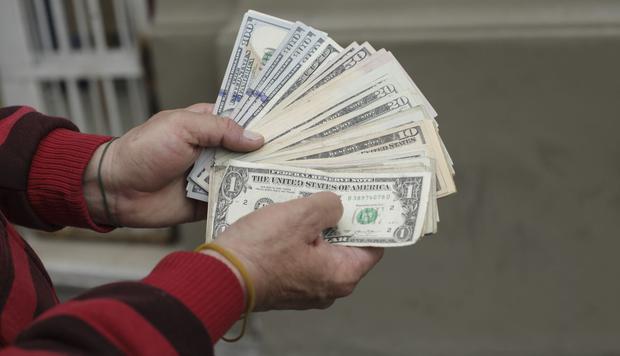 Una personas sosteniendo varios billetes de dólares (Foto: GEC)