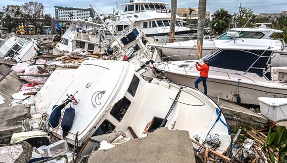 Un hombre toma fotos de los barcos dañados por el huracán Ian en Fort Myers, Florida, el 29 de septiembre de 2022. (GIORGIO VIERA / AFP).