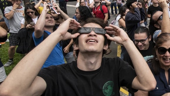 Un joven protegiendo su vista con unos lentes especiales mientras observa un eclipse solar (Foto: AFP)