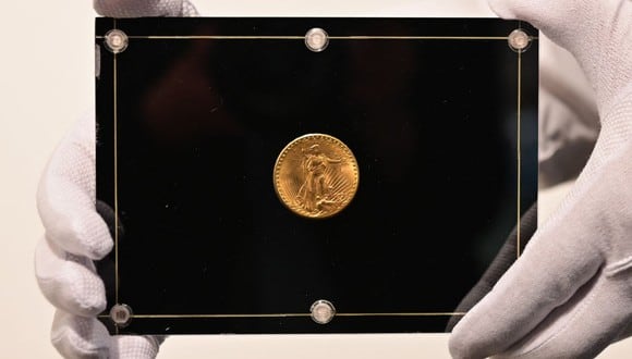 Un empleado de Sotheby's sostiene una moneda Double Eagle de 1933 durante los "Tres tesoros recopilados por Stuart Weitzman", una subasta en vivo dedicada a tres tesoros de la colección personal del diseñador de moda y coleccionista, en Sotheby's, el 11 de marzo de 2021 en Nueva York (Foto: Angela Weiss / AFP)