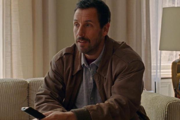 Adam Sandler as Danny, holding a remote control in the film "The Meyerowitzes" (Photo: IAC Films)