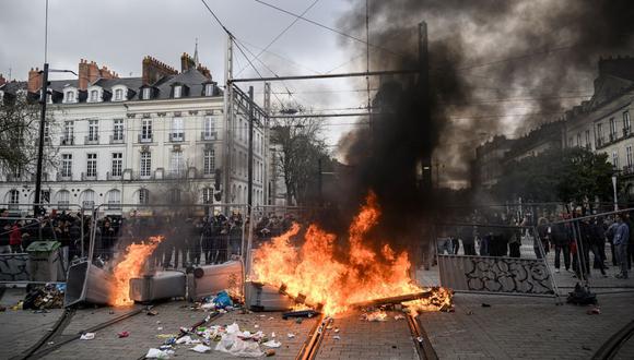 Los manifestantes se paran junto a una barricada en llamas durante una manifestación en Nantes, en el oeste de Francia, el 18 de marzo de 2023 (Foto: Loic Venance / AFP)