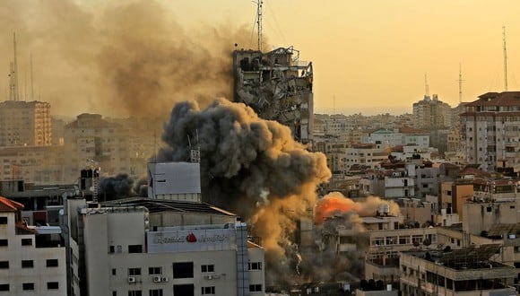 Denso humo y fuego se elevan desde la torre Al-Sharouk mientras se derrumba después de ser golpeada por un ataque aéreo israelí, en la ciudad de Gaza, el 12 de mayo de 2021. (AFP).