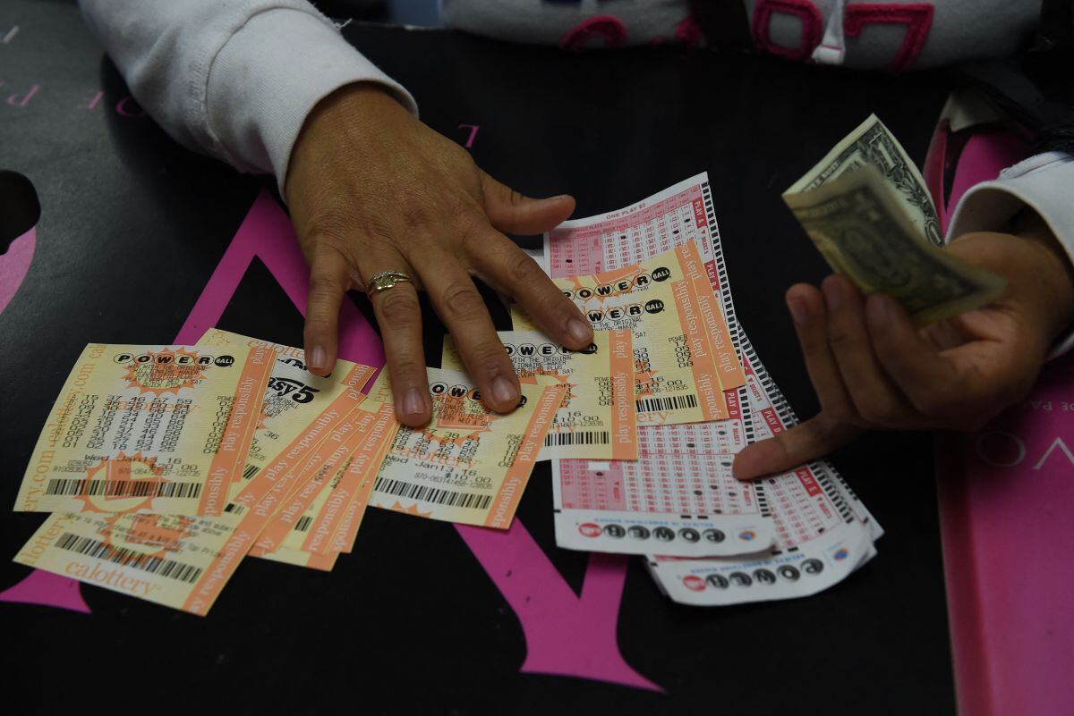Una clienta recoge sus boletos de lotería Powerball de California en la famosa licorería Bluebird, considerada un minorista afortunado de boletos, en Hawthorne, California, el 13 de enero de 2016 (Foto: Marc Ralston / AFP)