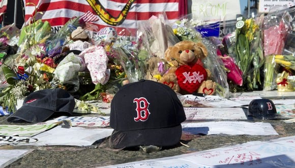 Una gorra de los Medias Rojas de Boston a la izquierda en un monumento improvisado en la ruta del maratón de Boston el 18 de abril de 2013 en Boston (Foto: Don Emmert / AFP)