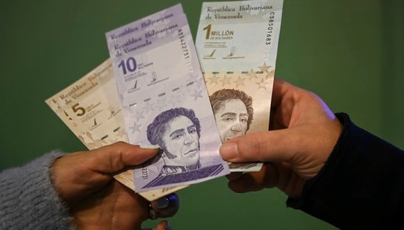 People show the new five and ten bolivar bank notes (L and C) put in circulation by the Central Bank of Venezuela as part of the currency reconversion, and another of one million bolivares that will continue to circulate with a value of one bolivar, after making a cash withdrawal at an ATM in Caracas on October 1, 2021. - The official exchange rate of the Venezuelan bolivar went from 4.18 million to the US dollar overnight to just 4.18 as the impoverished country slashed six zeroes off its inflation-battered currency Friday to simplify transactions. (Photo by Yuri CORTEZ / AFP)