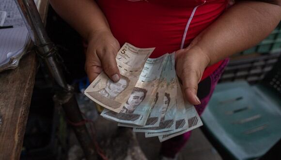 Una mujer cuenta billetes de bolívar en un mercado callejero en la comunidad José Félix Ribas en el barrio de Petare en Caracas el 5 de noviembre de 2022.
