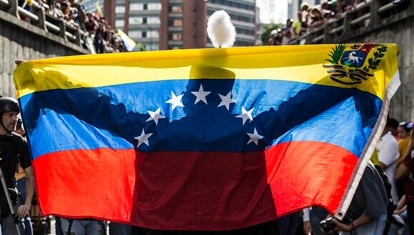 Una persona extiende una bandera venezolana ante decenas de manifestantes durante una protesta antigubernamental, el 24 de julio de 2017, en Caracas (Venezuela). (Foto: EFE)