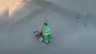 Trabajador de limpieza complace a un perrito callejero y le rasca la panza con su escoba
