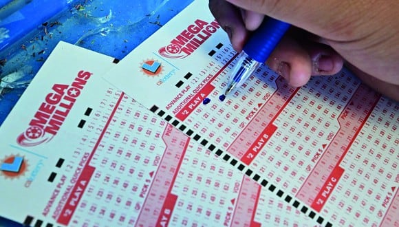 Un comprador selecciona los números en los boletos para la lotería Mega Millions en Los Ángeles, California, el 4 de agosto de 2023 (Foto: AFP)
