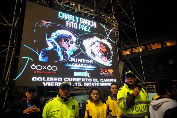 Officers in front of a poster for the Charly García and Fito Páez concert, after the announcement that García had fallen ill on the way to the concert and had been rushed to a clinic in Bogotá, on November 15, 2013 (Photo: Guillermo Legaria / AFP)