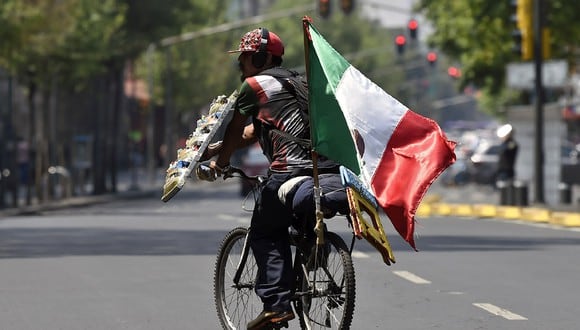 Un vendedor ambulante ofrece sus productos mientras monta su bicicleta con una bandera mexicana en la Ciudad de México durante la nueva pandemia de coronavirus COVID-19. (Foto: AFP/Alfredo ESTRELLA)