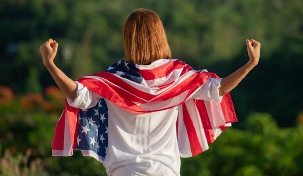 Una mujer con la bandera de Estados Unidos en su espalda muy feliz y orgullosa de vivir en el país norteamericano  (Foto: Freepik)
