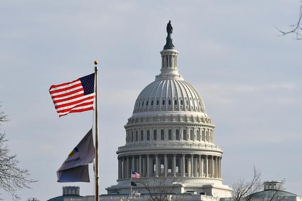 Una bandera de Estados Unidos ondea frente al Capitolio el 14 de enero de 2022. (MANDEL NGAN / AFP).
