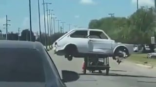 Conductor capta a reciclador llevando el esqueleto de un carro en su triciclo en una carretera de Argentina