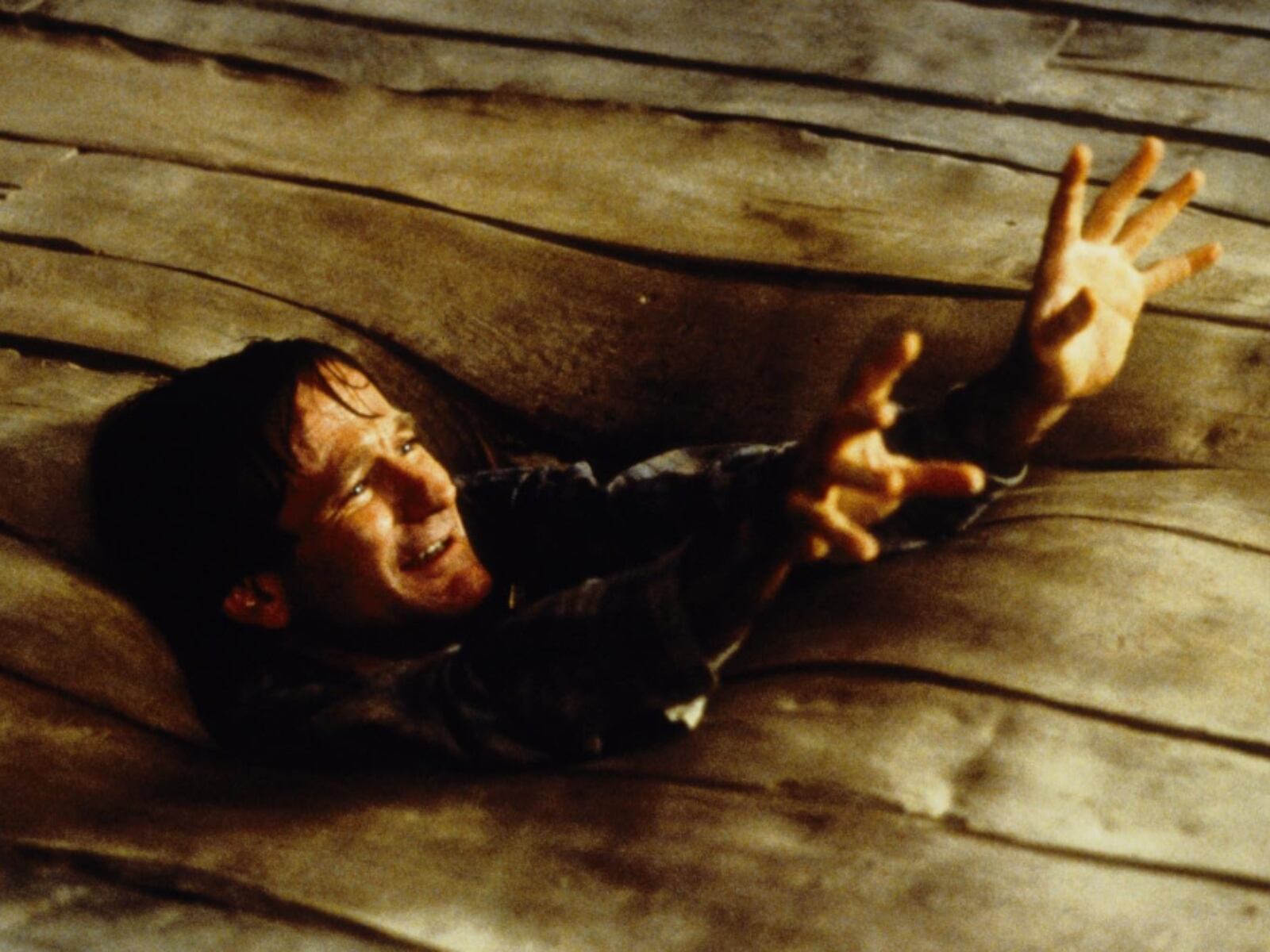 Robin Williams siendo absorbido por el piso de madera en "Jumanji". En la secuela, se iba a convertir en una rana (Foto: Teitler Film)