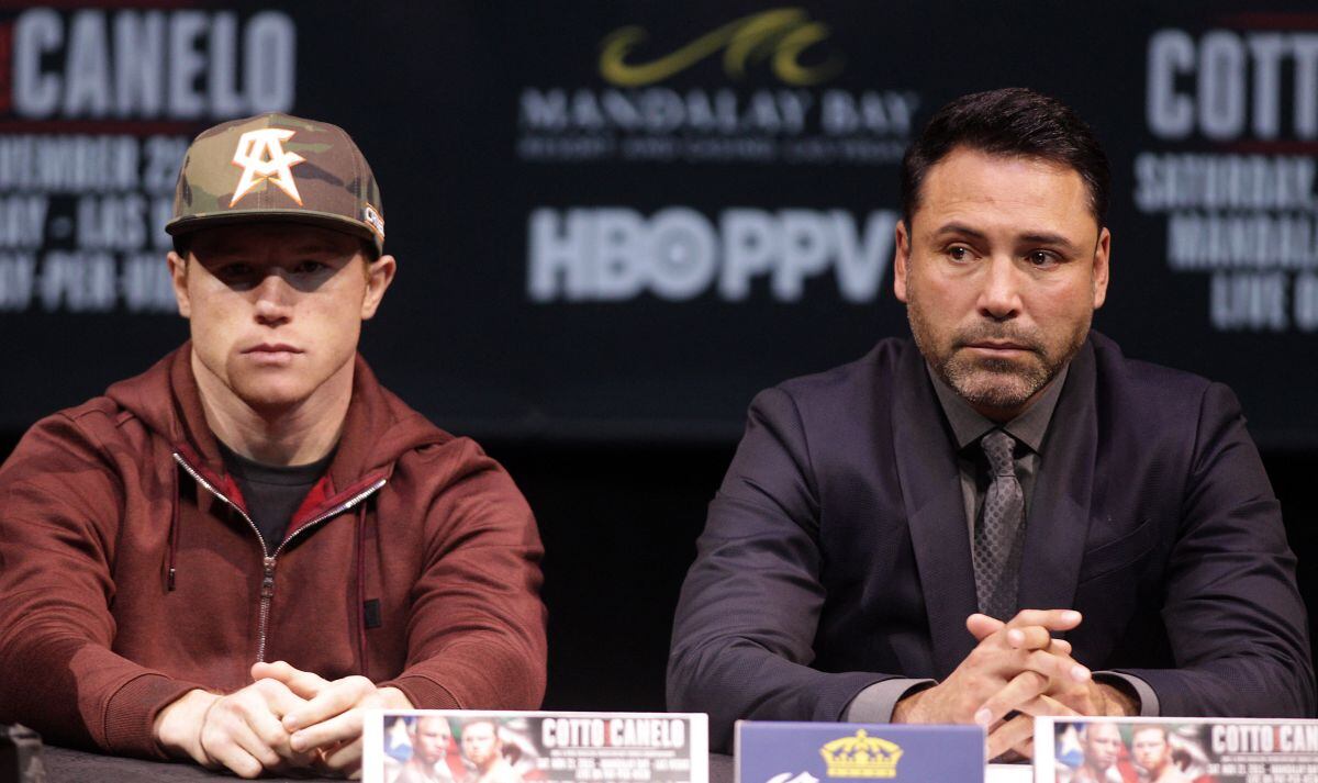 La vez que Saúl 'Canelo' Álvarez y el promotor Oscar de la Hoya escuchaban al ex campeón mundial de peso mediano del CMB Miguel Cotto, Puerto Rico, durante su conferencia de prensa en Las Vegas, Nevada, el 18 de noviembre de 2015 (Foto: John Gurzinski / AFP)