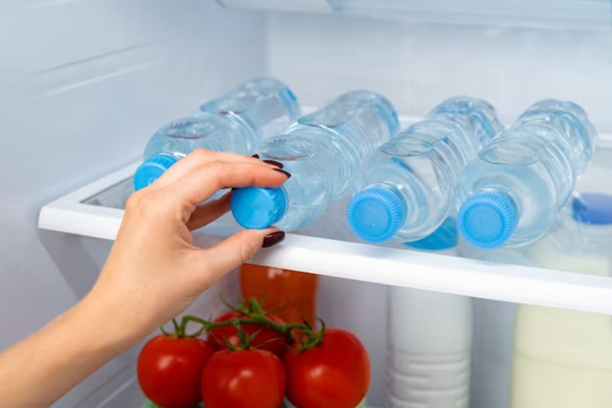 Una mujer sacando una botella llena de agua helada de la nevera (Foto: Freepik)