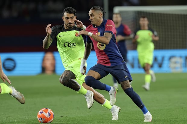 El delantero brasileño del Barcelona #11 Raphinha (d) disputa el balón con el centrocampista español del Real Mallorca #18 Antonio Sánchez durante el partido de fútbol de la liga española entre el FC Barcelona y el RCD Mallorca en el Estadi Olímpic Lluis Companys de Barcelona, el 22 de abril de 2025. (Foto de LLUIS GENE / AFP)