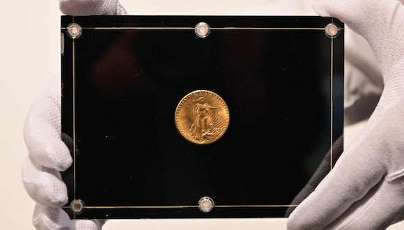 Un empleado de Sotheby's sostiene una moneda Double Eagle de 1933 durante los "Tres tesoros recopilados por Stuart Weitzman", una subasta en vivo dedicada a tres tesoros de la colección personal del diseñador de moda y coleccionista, en Sotheby's, el 11 de marzo de 2021 en Nueva York (Foto: Angela Weiss / AFP)