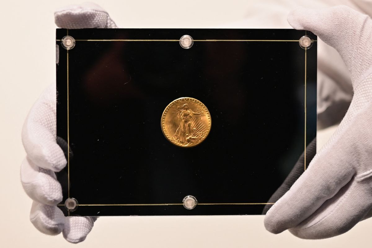 Un empleado de Sotheby's sostiene una moneda Double Eagle de 1933 durante los "Tres tesoros recopilados por Stuart Weitzman", una subasta en vivo dedicada a tres tesoros de la colección personal del diseñador de moda y coleccionista, en Sotheby's, el 11 de marzo de 2021 en Nueva York (Foto: Angela Weiss / AFP)