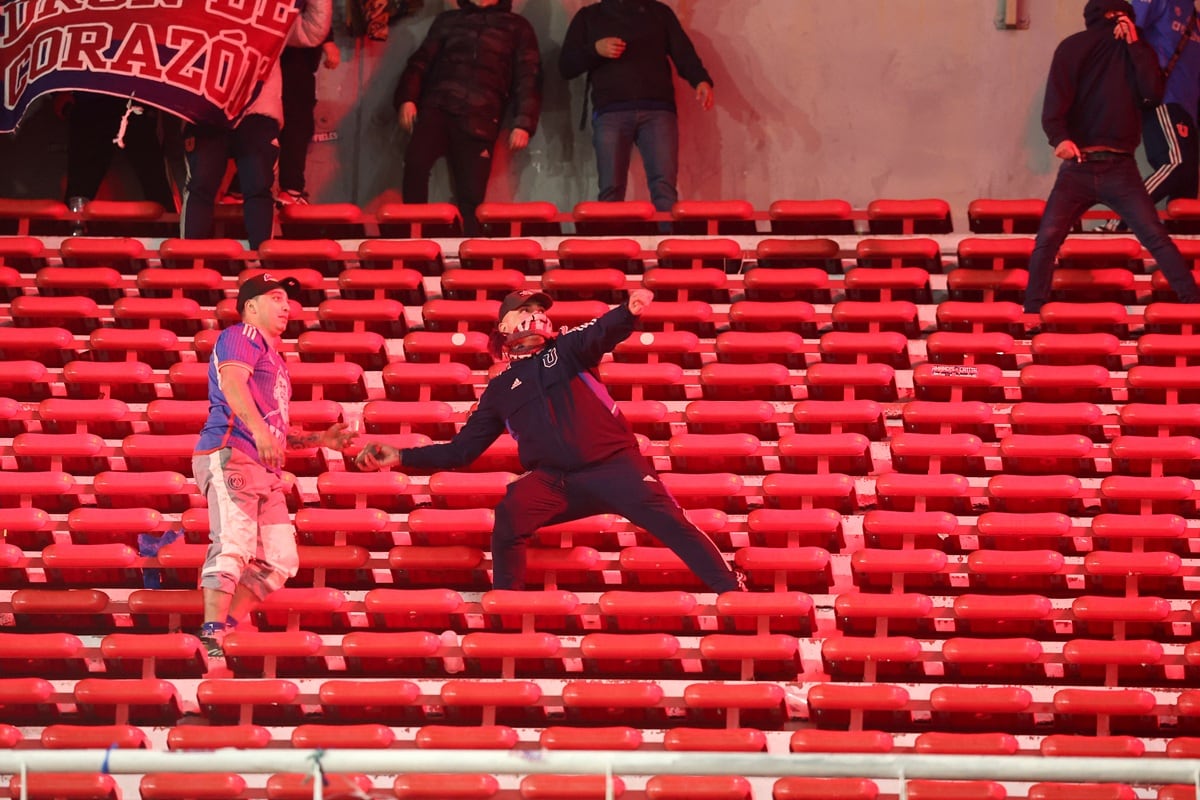 Un fanático de la Universidad de Chile se prepara para lanzar una piedra durante el partido entre Independiente y la U de Chile, en el estadio Libertadores de América de Avellaneda, Argentina, el 20 de agosto de 2025. (Foto de Alejandro PAGNI / AFP)