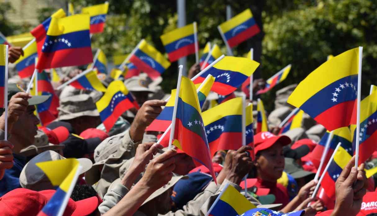 Los partidarios del presidente venezolano Nicolás Maduro ondean banderas nacionales cuando se reúnen para conmemorar el vigésimo aniversario del ascenso del poder del difunto Hugo Chávez. (Foto: AFP)