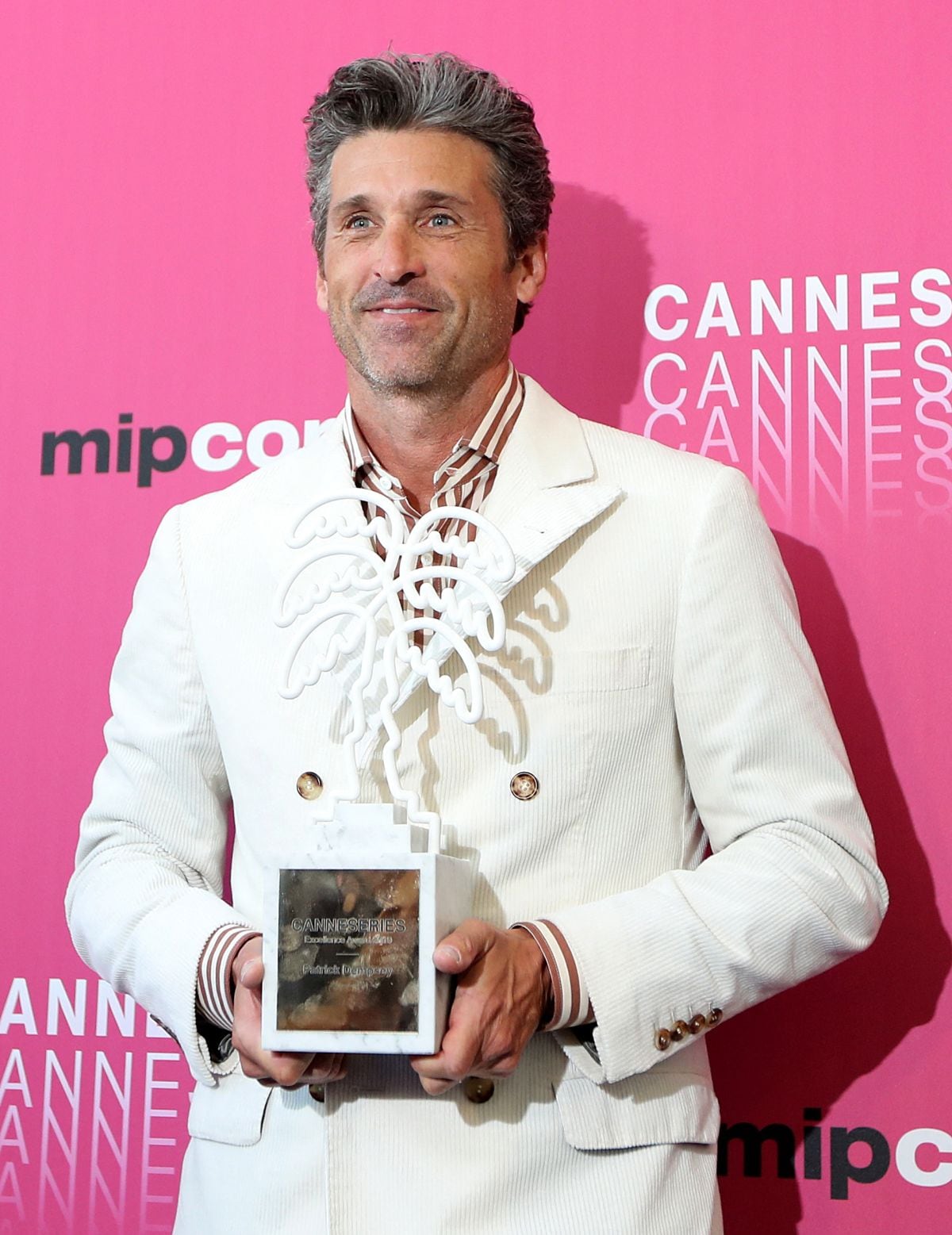 Patrick Dempsey posa con el trofeo 'Premio a la Excelencia' por su carrera en la televisión y el cine en MIPCOM, el mercado de televisión y entretenimiento más grande del mundo, el 14 de octubre de 2019 en Cannes (Foto: Valery Hache / AFP)
