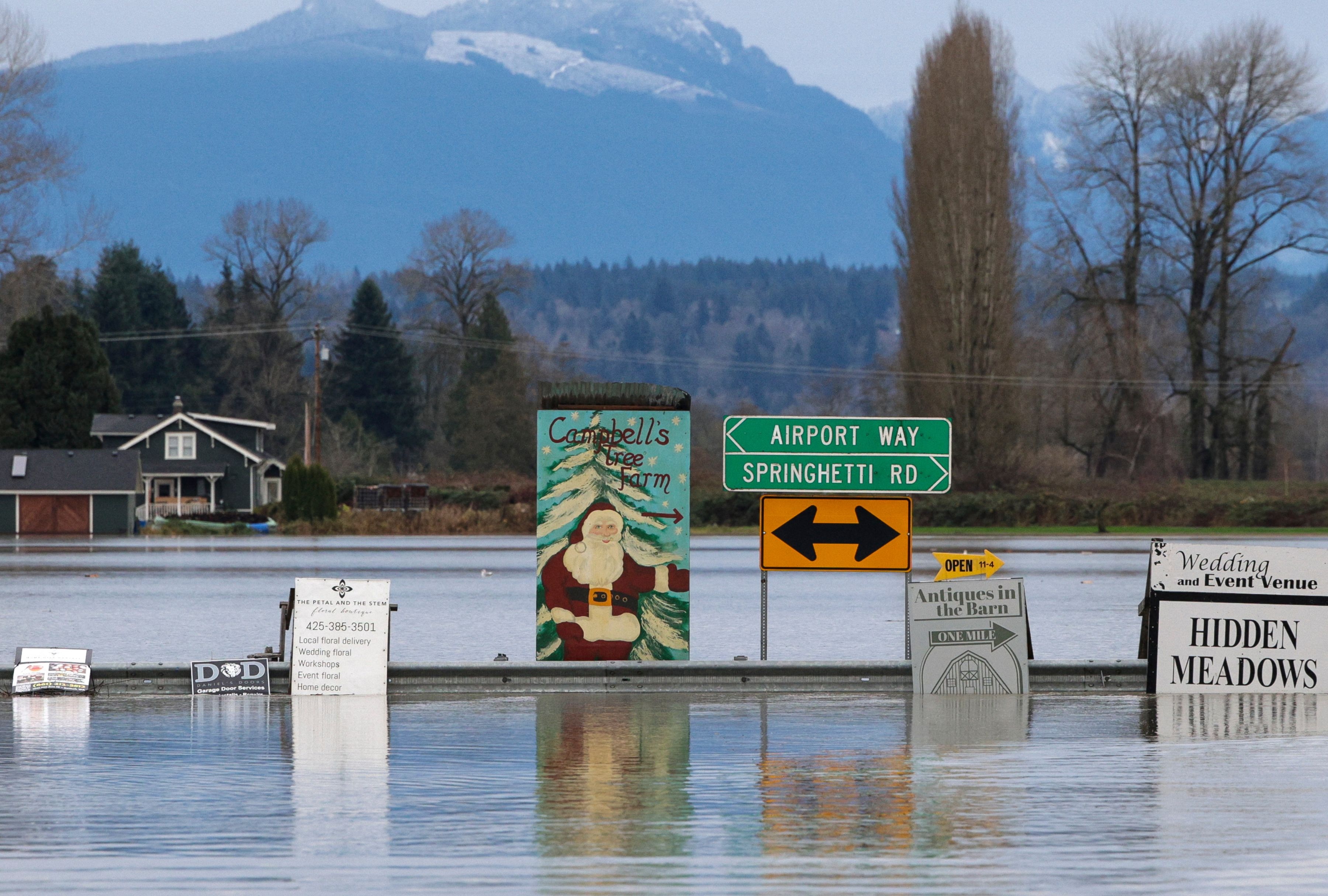 A sign for a Christmas tree farm is pictured as flood waters from the Snohomish River cover Marsh Road off State Route 9 in Snohomish, Washington, on December 2025. (Photo by JASON REDMOND / AFP)
