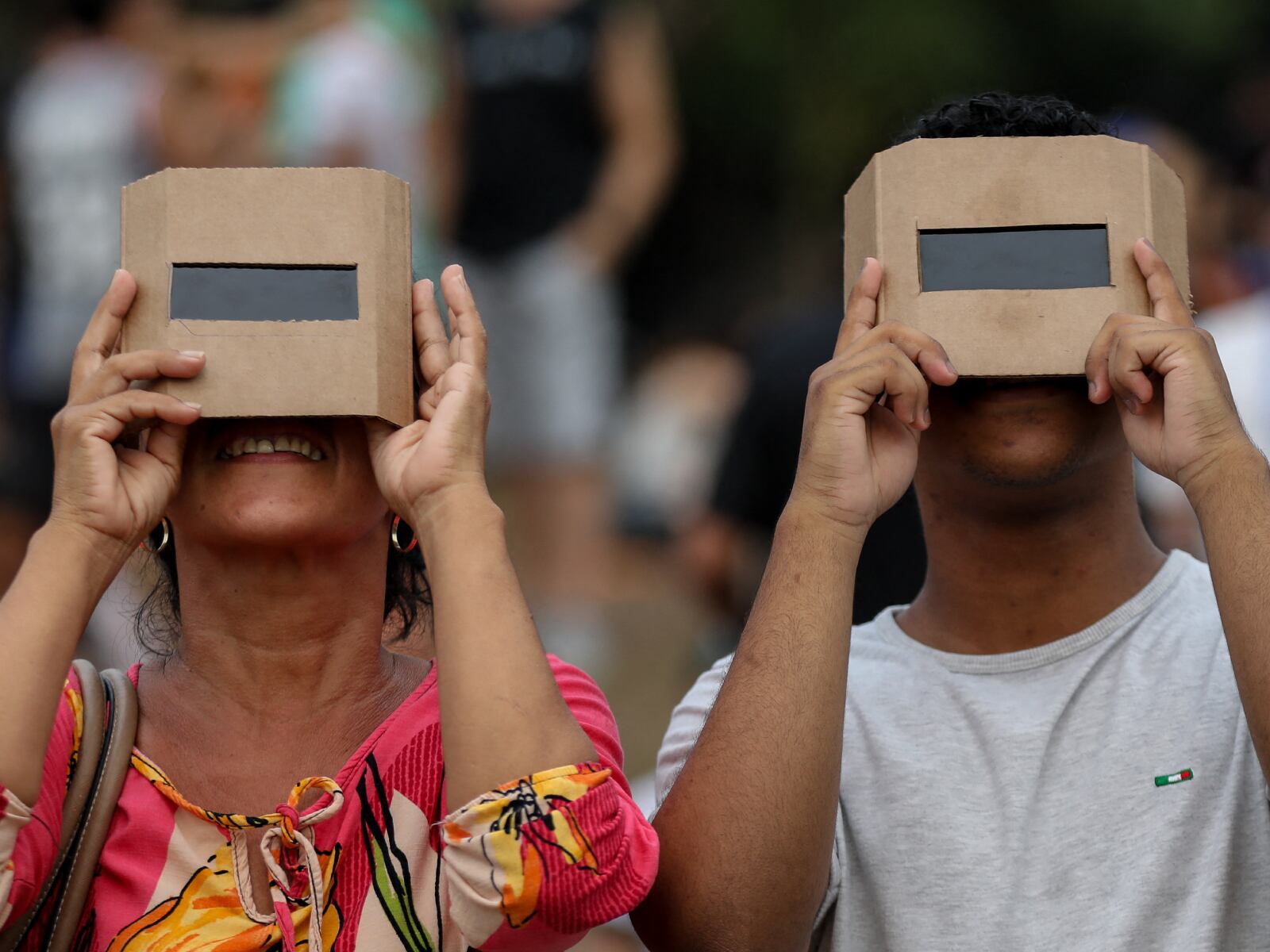 Dos personas protegiendo su vista con unos lentes especiales mientras observa un eclipse solar (Foto: AFP)