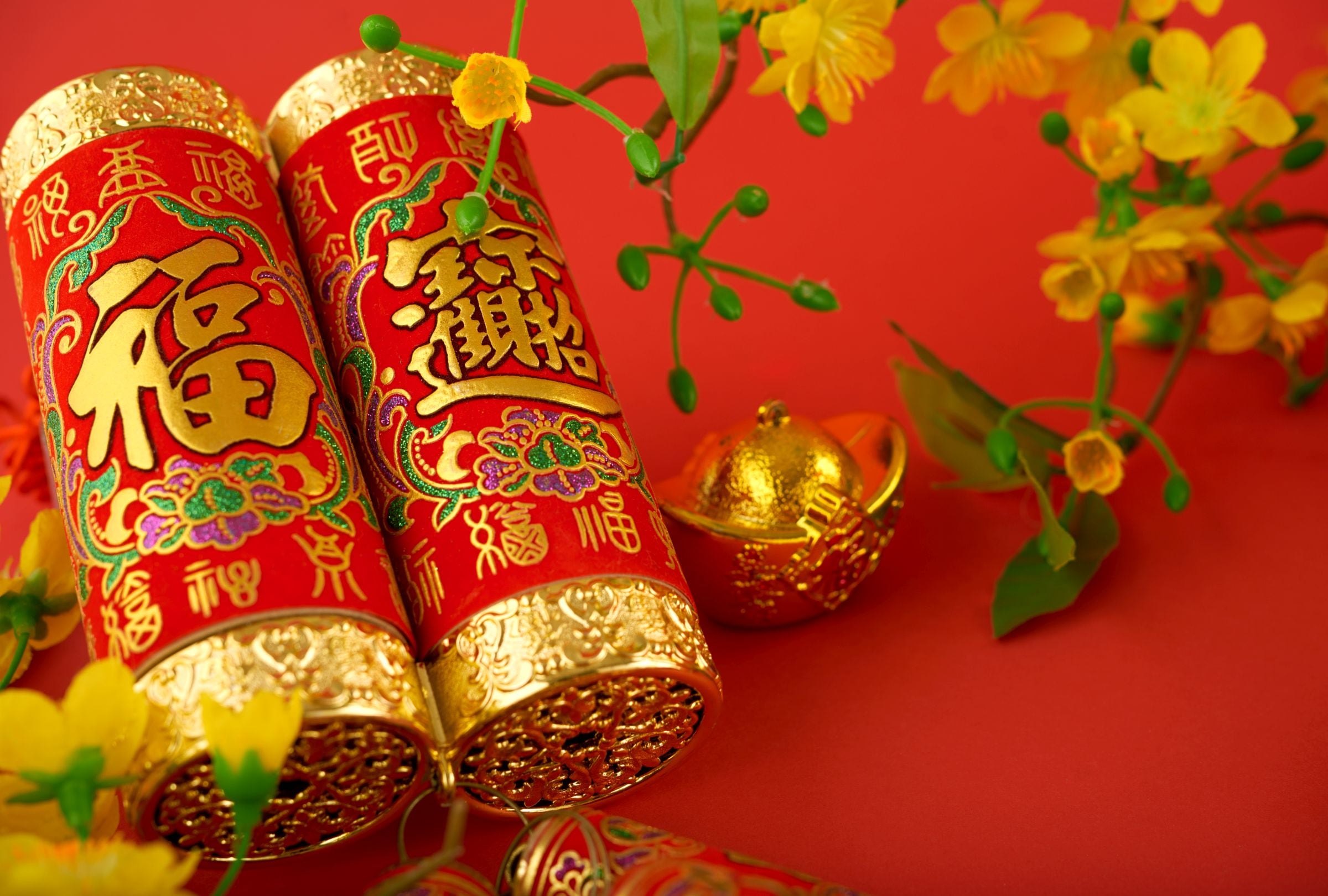 Imagen de primer plano de petardos chinos con inscripción de mejores deseos y lingotes de oro (Foto: Freepik)