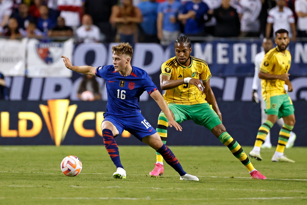 El centrocampista estadounidense Aidan Morris (L) lucha por el balón con el centrocampista jamaicano Kevon Lambert (C) durante el partido de fútbol del Grupo A de la Copa Oro Concacaf 2023 entre Estados Unidos y Jamaica en el estadio Soldier Field de Chicago, Illinois, el 24 de junio de 2023. | Crédito: Kamil Krzaczynski / AFP