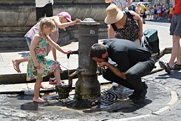 Los turistas se refrescan y beben en una fuente en Roma, en medio de una feroz ola de calor que arrasa Europa, el 19 de julio de 2022 (Foto: Andreas Solaro / AFP)